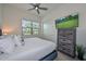 Well-lit bedroom with a ceiling fan, dresser with a TV, and a window with a view at 18233 W Hope Dr, Goodyear, AZ 85338