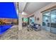 The covered patio has a dining area, comfortable seating, a tv, and access to a pool and jacuzzi at 18233 W Hope Dr, Goodyear, AZ 85338