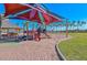 Community playground features a colorful shade canopy, modern play structures, and sandy play area near lake at 18233 W Hope Dr, Goodyear, AZ 85338