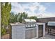 Outdoor kitchen featuring a built-in grill, stone accents, and a small fridge at 20631 W Minnezona Ave, Buckeye, AZ 85396