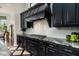 Gourmet kitchen featuring black cabinets, granite counters, subway tile backsplash, and gas cooktop at 21235 N 80Th Way, Scottsdale, AZ 85255