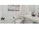 Neutral powder room with pedestal sink, black hardware and decorative wall art at 22656 E Marsh Rd, Queen Creek, AZ 85142