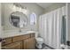 Charming bathroom with a round mirror, wood vanity, tub, and an arched window at 2673 E Remington Pl, Chandler, AZ 85286