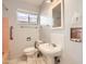 This bathroom features a white sink, toilet, pink tiles, a large window, and storage cabinets at 302 E Orange Dr, Phoenix, AZ 85012
