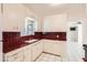 Well-lit kitchen featuring white cabinets, striking red countertops, and sleek white tiled flooring at 302 E Orange Dr, Phoenix, AZ 85012