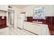 Bright kitchen featuring white cabinetry, contrasting red countertops and backsplash, with white tile flooring at 302 E Orange Dr, Phoenix, AZ 85012
