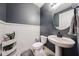 Stylish powder room with dark gray walls, a pedestal sink, and white wainscoting, offering a modern touch at 3907 S 75Th Dr, Phoenix, AZ 85043