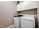Close up of a well-equipped laundry area with appliances and overhead cabinets for organized storage at 3907 S 75Th Dr, Phoenix, AZ 85043