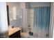 Clean bathroom with a sink and cabinet area, toilet, and shower/tub combo with a blue shower curtain at 429 N San Ricardo N Trl, Casa Grande, AZ 85194