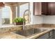 Close up of kitchen sink featuring stainless steel fixtures, granite countertops, and view of the backyard at 43142 N Outer Bank Dr, Anthem, AZ 85086
