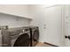 Convenient laundry room featuring modern washer and dryer, plus additional shelving at 43142 N Outer Bank Dr, Anthem, AZ 85086