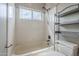 Bright bathroom features a tiled shower and tub combination with a modern shower head and shelving unit for storage at 4864 E Eden Dr, Cave Creek, AZ 85331