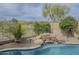 Rock waterfall feature spills into the inviting private pool, surrounded by decorative landscaping and rocks at 4864 E Eden Dr, Cave Creek, AZ 85331
