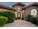Elegant stone home with a decorative front door framed by lush landscaping and stone pathway at 7635 E Sweetwater Ave, Scottsdale, AZ 85260