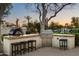 The outdoor kitchen area features a pizza oven, grill, counter seating, and mature landscaping at 7635 E Sweetwater Ave, Scottsdale, AZ 85260