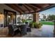 Charming covered patio featuring stone pillars and outdoor seating overlooking the manicured lawn at 7635 E Sweetwater Ave, Scottsdale, AZ 85260