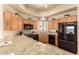 Spacious kitchen featuring custom wood cabinets, granite countertops, and modern black appliances at 8785 E Sandtrap Ct, Gold Canyon, AZ 85118