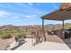 Relaxing outdoor area with a stone fireplace, seating area, and stunning views of the golf course and desert landscape at 9620 E Roadrunner Dr, Scottsdale, AZ 85262