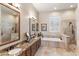 Elegant bathroom featuring double vanity, granite countertops, soaking tub, and separate walk-in shower with tile surround at 9620 E Roadrunner Dr, Scottsdale, AZ 85262
