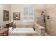 Luxurious bathroom showcasing a soaking tub beneath a window and a separate walk-in shower with travertine tile surround at 9620 E Roadrunner Dr, Scottsdale, AZ 85262