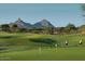 Scenic view of golfers enjoying a round of golf on a lush green course, with majestic mountains in the backdrop at 9620 E Roadrunner Dr, Scottsdale, AZ 85262