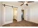 Spacious bedroom featuring carpet flooring, ceiling fan, ensuite bathroom with modern sliding barn door at 1055 W Dragoon Ave, Mesa, AZ 85210