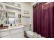 Traditional bathroom featuring a vanity with decorative items, alongside a toilet and shower with a maroon curtain at 10855 W Buccaneer Dr, Sun City, AZ 85351