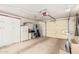 Garage featuring a large garage door, white storage cabinets, and a white refrigerator at 10855 W Buccaneer Dr, Sun City, AZ 85351