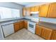 Well-lit kitchen with tile floors, wood cabinets, a breakfast bar, and white appliances at 1366 E Desert Fern Trl, Casa Grande, AZ 85122