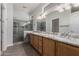 Bright bathroom features double sinks, granite countertops, a large mirror and a glass-enclosed walk-in shower at 15136 W Cactus Ridge Way, Surprise, AZ 85374