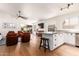 Open living room with hardwood floors, fan, TV, leather chairs, and kitchen in background at 1701 E Countrywalk Ln, Chandler, AZ 85225