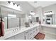 Bright bathroom features a dual sink vanity with a makeup vanity area and a glass shower at 18394 W Lupine Ave, Goodyear, AZ 85338