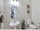 Powder room features a pedestal sink, round mirror and decorative accents at 18394 W Lupine Ave, Goodyear, AZ 85338