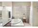Bright bathroom featuring a soaking tub, glass block windows, tiled shower, and granite countertop at 3373 E Sports Dr, Gilbert, AZ 85298