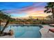 Resort-style backyard with a sparkling pool, mature landscaping, and a serene ambiance enhanced by a colorful sunset at 3373 E Sports Dr, Gilbert, AZ 85298