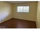 Bedroom features a window with blinds and wood-look flooring with yellow walls and baseboards at 355 E Thomas Rd # B207, Phoenix, AZ 85012