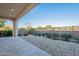 An open-air back patio with stone pavers and a rock garden featuring drought-tolerant plants beyond the wrought iron fence at 36169 N Serrano Ave, Queen Creek, AZ 85140