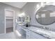 Modern bathroom with double granite-top vanity, round mirrors and open closet area at 36169 N Serrano Ave, Queen Creek, AZ 85140
