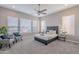 A modern bedroom with neutral colors, many windows, a ceiling fan, and cozy seating at 36169 N Serrano Ave, Queen Creek, AZ 85140