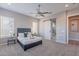 Bedroom with barn door to bathroom, neutral colors, ceiling fan, and king-size bed at 36169 N Serrano Ave, Queen Creek, AZ 85140