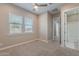 Bedroom with two windows, ceiling fan, light-colored carpet, and an ensuite bathroom at 36169 N Serrano Ave, Queen Creek, AZ 85140