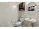 Cozy powder room with a pedestal sink, decorative mirror, and a charming storage cabinet at 608 E Pasaro Dr, Phoenix, AZ 85085