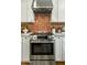 Close-up of a stainless steel stove and hood with decorative red tile backsplash in updated kitchen at 8361 E Via De Viva --, Scottsdale, AZ 85258