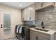 Laundry room features modern washer/dryer, stylish cabinets, backsplash, sink, and access to exterior at 10620 N 84Th St, Scottsdale, AZ 85260