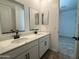 Modern bathroom featuring double sinks, quartz countertop, dark hardware, and a framed mirror at 15786 W Cheryl Dr, Waddell, AZ 85355