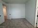A well-lit bedroom featuring a neutral carpet and an open doorway at 15786 W Cheryl Dr, Waddell, AZ 85355