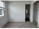 A bright bedroom with neutral carpet, a window with blinds, closet, and an attached bathroom at 15786 W Cheryl Dr, Waddell, AZ 85355