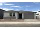 A charming single-story home featuring a gray color palette, attached two-car garage, and gravel landscaping at 15786 W Cheryl Dr, Waddell, AZ 85355