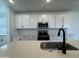 Close-up of a modern kitchen featuring white cabinets, stainless steel appliances, and a sleek faucet at 15786 W Cheryl Dr, Waddell, AZ 85355