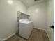 Well-lit laundry room with wooden floors, washer, dryer, and white shelving for optimal storage at 15786 W Cheryl Dr, Waddell, AZ 85355